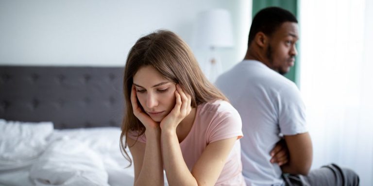 Upset Caucasian Woman Sitting Back To Back On Bed With Her Black Husband.jpg