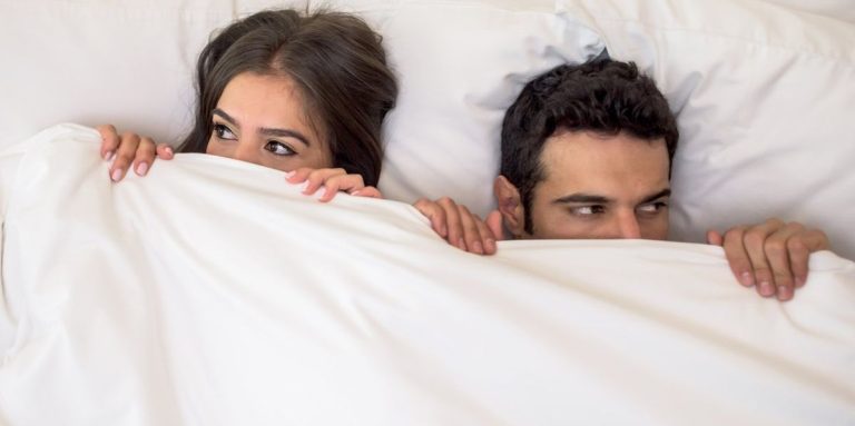 Portrait Of A Scared Couple In Bed With Man And Woman Looking Very Anxious.jpg