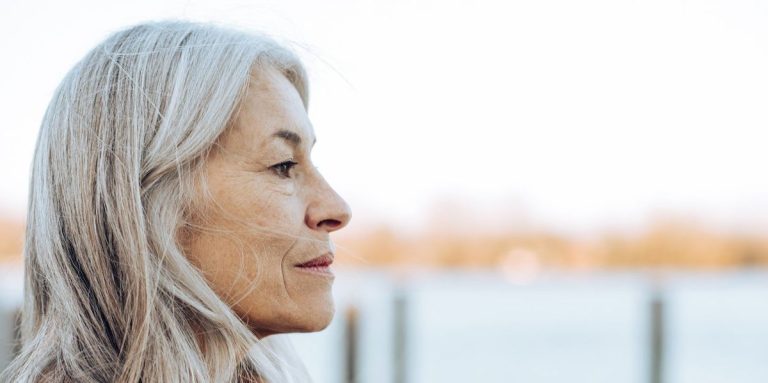 Thoughtful Mature Woman Standing On The Beach And Looking At The Distance.jpg